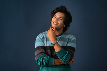 Wall Mural - Portrait of a young man thinking on a dark background