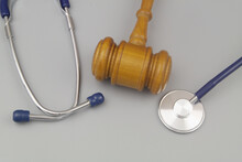 Wooden Judge Gavel And Stethoscope On Gray Background. Malpractice Concept.
