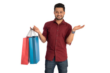 Young handsome man holding and posing with shopping bags on a white background