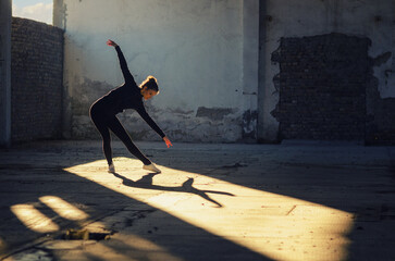 Ballerina dancing in an abandoned building on a sunny day