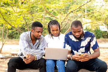Group of learning millennial african american computer science students at university or college using laptop outside school campus
