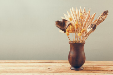 Dried flowers in vase on wooden table. Autumn home decoration