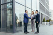 © Liubomir - Business meet, colleagues happy team meet outside office, greet shake hands, diverse employees in business suit, man and woman business people