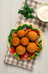 Wall Mural - Tortillas, wrapped falafel balls, with fresh vegetables, vegetarian healthy food, on a wooden white background, no people, selective focus.