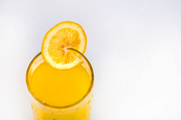 Lemon juice and a slice of lemon. Lemonade close-up on a white background. Cold summer drink in a glass with lemon juice. A piece of lemon in a glass.