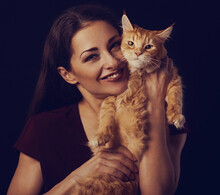 Beautiful Make-up Woman With Brown Long Hair Holding And Tender Hugging With Love Her Red Maine Coon Kitten. Closeup Toned Vintage Color Portrait. Art