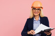 © anatoliycherkas - Portrait of attractive mature business woman architect or engineer in glasses use folder with documents on the pink background
