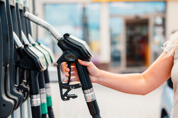 Wall Mural - Closeup of woman pumping gasoline fuel in car at gas station. Petrol or gasoline being pumped into a motor. Transport concept