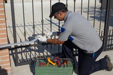 Electrician At Work With Tools Of The Trade While Assembling And Repairing The Motor Of An Automatic Gate. Do It Yourself Homework
