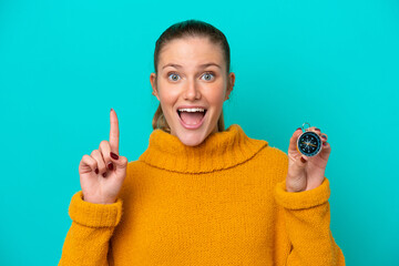 Young caucasian woman holding compass isolated on blue background pointing up a great idea