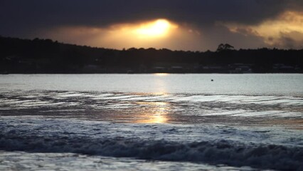 Poster - sunrise reflecting on the beach with golden light as waves roll in and water moves on the sand, calming waves	
