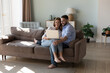 © fizkes - Couple sit on sofa use laptop make on-line purchase, order services, buy goods, search home decorations ideas on internet spend time with modern technology. E-commerce clients for comfort life concept