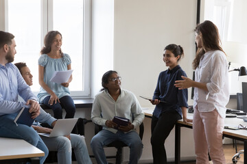 Canvas Print - Happy diverse business group with Indian female leader laughing on corporate meeting during informal communication, share funny ideas, joking, brainstorming. Teamwork, positive employees and workflow