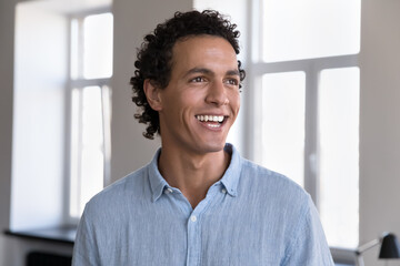 Handsome Hispanic businessman in shirt standing indoor smile staring aside feels happy. Professional occupation person, business aspirations, advisory agency representative head shot portrait concept