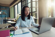 © Kostiantyn - Attractive asian businesswoman working on laptop and making notes at modern office