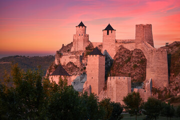 Wall Mural - The medieval fortress of Golubac illuminated of pink light of setting sun against colorful clouds in background. Famous tourist place, Serbia.