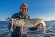 Success pike fishing. Fisherman in sunglasses holds muskie fish