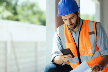 A portrait of an industrial man engineer with smartphone in a factory, working.