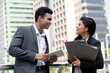 © Atstock Productions - Indian businessman talking with businesswoman colleague outdoors with city office buildings in background