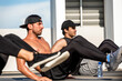 © Atstock Productions - Multiracial dedicated male athletes wearing caps and practicing bodyweight exercise on building rooftop on sunny day
