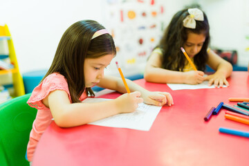 Wall Mural - Kindergarten students coloring and drawing in their desks at school