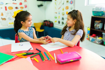 Little girls coloring and learning to share in preschool