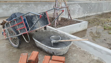 A pile of building materials, bucket mortar mixed and heap of red bricks at construction site.