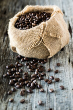 A Burlap Sack Filled With Coffee Beans Wth Some Spilled Out In Front.