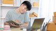 © Puwasit Inyavileart - Man selling products online was talking on the phone or chat to receive an order from a customer and list in a notebook, Online shopping SME entrepreneur, Packing box, Sell online, Freelance working.