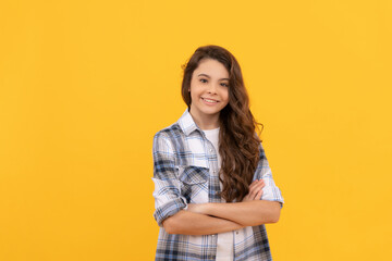 happy teen girl in checkered shirt with long curly hair on yellow background