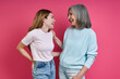 Leinwandbild Motiv Happy mother and adult daughter looking at each other against pink background
