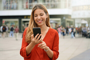 Wall Mural - Portrait of smiling young woman using a smartphone app in Berlin, Germany