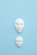 Two White Mask With Neutral Facial Expression On Blue Background