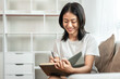 © Katcha - Half-Japanese woman is writing a diary on the sofa in her living room, Daily routine record, Relaxing time on vacation, Happy time, Living at home, Comfortable corner