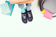 Kid wearing different pair of socks. Child in mismatched socks and colorful sneakers sitting on white background, with backpack, books and school supplies. Top view