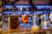 Large Glass Jugs, Jars Of Apple Juice, Lemonade With Lemon, An Alcoholic Cocktail With A Straw Are On The Bar In The Restaurant. Food Photography.