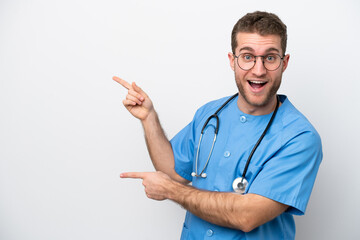 Wall Mural - Young surgeon doctor caucasian man isolated on white background surprised and pointing side