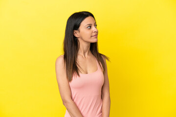 Wall Mural - Young caucasian woman isolated on yellow background looking to the side