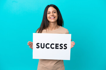 Wall Mural - Young woman over isolated background holding a placard with text SUCCESS with happy expression