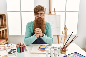 Wall Mural - Redhead man with long beard painting clay bowl at art studio depressed and worry for distress, crying angry and afraid. sad expression.