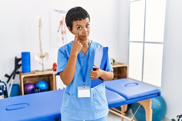 Canvas Print - Young hispanic woman with short hair working at pain recovery clinic pointing to the eye watching you gesture, suspicious expression