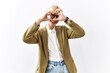 © Krakenimages.com - Beautiful caucasian business woman standing over isolated background doing heart shape with hand and fingers smiling looking through sign