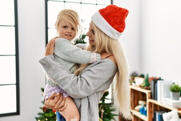 Wall Mural - Mother and daughter hugging each other standing by christmas tree at home