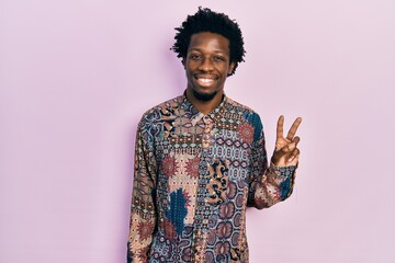 Canvas Print - Young african american man wearing casual clothes smiling with happy face winking at the camera doing victory sign. number two.