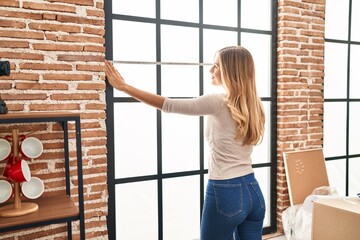 Wall Mural - Young blonde woman smiling confident measuring window at new home