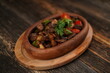 Saute meat in a stew on a wooden background. Meat saute made with beef, mushroom, onion, green pepper and tomatoes. A delicious traditional Turkish food name is Guvec. T