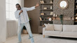 © Yuliia - Mature crazy funny African American excited senior retired man washing floor in home apartment active dancing moving to music has fun doing cleaning housekeeping chores use mop like microphone singing