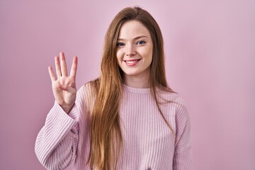 Wall Mural - Young caucasian woman standing over pink background showing and pointing up with fingers number four while smiling confident and happy.