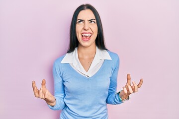 Canvas Print - Beautiful woman with blue eyes standing over pink background crazy and mad shouting and yelling with aggressive expression and arms raised. frustration concept.