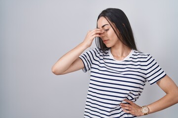 Poster - Young brunette woman wearing striped t shirt tired rubbing nose and eyes feeling fatigue and headache. stress and frustration concept.